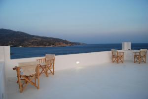 a group of chairs and tables on a balcony with the ocean at Ios art villa in Ios Chora