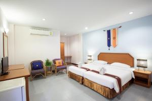 a hotel room with a large bed and two chairs at Eastiny Resort & Spa in Nong Prue