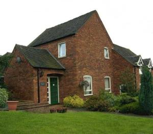 a brick house with a green door in a yard at Birtley House Guest House B&B in Telford