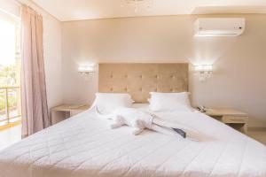 a large white bed with white sheets and pillows at Marruá Hotel in Bonito