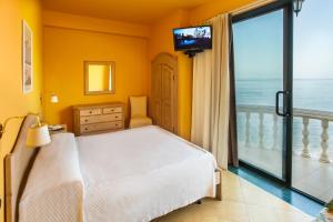Hotel La Playa Blanca في سانتو ستيفانو دي كاماسترا: غرفة نوم مع سرير وبلكونة مع تلفزيون