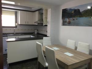 a kitchen with a wooden table and white chairs at Ruralfranxuli in Avellanes