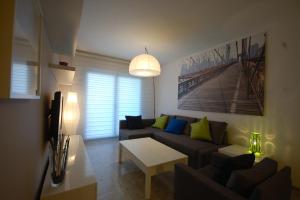 ein Wohnzimmer mit einem Sofa und einem Tisch in der Unterkunft Lets Holidays New Flat Beachfront In Castelldefels in Castelldefels