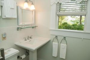 a white bathroom with a sink and a window at Orchard Inn in Saluda