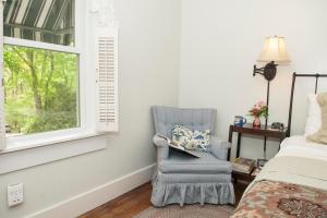 a bedroom with a blue chair and a window at Orchard Inn in Saluda