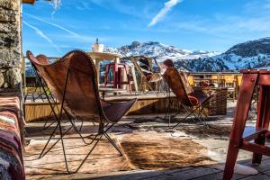 a man sitting in chairs on a deck with mountains at Hôtel Courcheneige in Courchevel