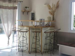 a kitchen with three bar stools in a room at Le Jardin Ombragé in Saint-Paul-dʼIzeaux