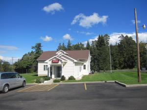 a white building with a car parked in a parking lot at Embassy Inn Motel Ithaca in Ithaca