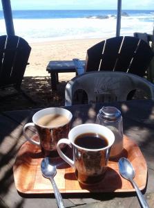 two cups of coffee on a wooden tray on the beach at Cafe Maya - Casa Acalli in Zipolite