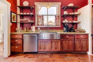 a kitchen with red walls and a stainless steel sink at Travis Street in Fredericksburg