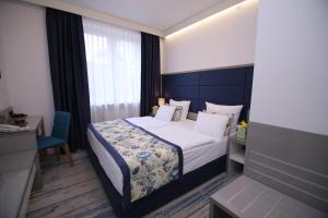 um quarto de hotel com uma cama e uma cadeira e uma janela em Old Town Hotel em Saraievo
