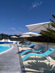 - une rangée de chaises et de parasols à côté de la piscine dans l'établissement Aubergerie, à Sauzon