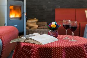un tavolo con un libro e due bicchieri di vino di Animae Natura Hotel & Chalet a Mezzana