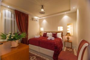Una habitación de hotel con una cama con sábanas rojas y toallas blancas. en Vila Tako - Hotel, en Tirana
