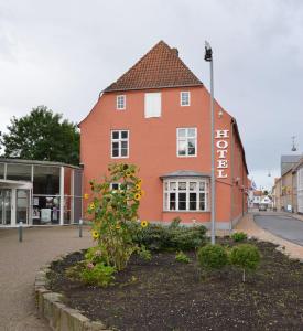 un edificio con un giardino fiorito di fronte ad esso di Hotel Harmonien a Haderslev