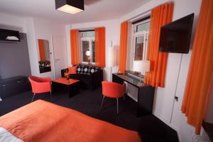 a bedroom with orange curtains and a bed and a desk at Hotel Harmonien in Haderslev