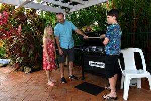 a man and two children standing in front of a grill at Waterfront Terraces in Cairns
