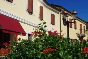 a building with red flowers in front of a building at Dependance Lipa in Basovizza
