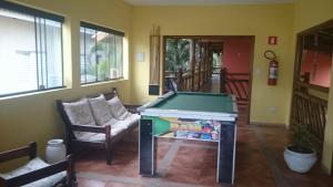 einen Billardtisch in einem Wohnzimmer mit 2 Stühlen in der Unterkunft Pousada Água Marinha in Caraguatatuba