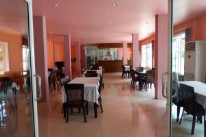 a dining room with tables and chairs and orange walls at Na Chaidej hotel in Suratthani