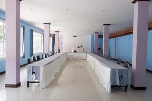 a long banquet hall with blue walls and tables and chairs at Na Chaidej hotel in Suratthani