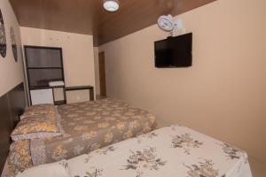 a bedroom with two beds and a flat screen tv at Pousada Primavera in Mucugê