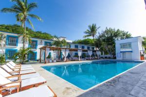 a pool in front of a house with lounge chairs at Hotel Santa Cruz Huatulco in Santa Cruz Huatulco