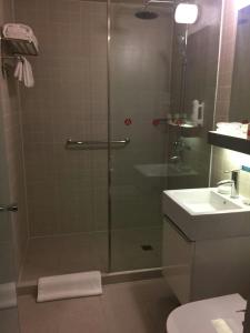 a shower with a glass door next to a sink at JinJiang Inn Pingyang Taiyuan Road Hotel in Taiyuan