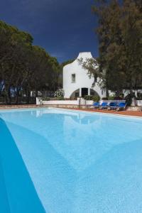 a large swimming pool in front of a white house at Hotel Mare Pineta in Santa Margherita di Pula