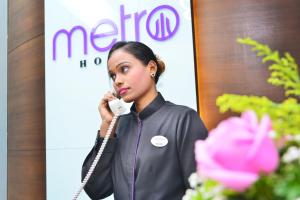 uma mulher a falar ao telefone em frente a uma placa em Metro Hotel Bukit Bintang em Kuala Lumpur