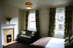 Gillygate Guest House في يورك: غرفة نوم بسرير وكرسي ومدفأة