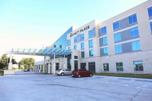 a building with a car parked in a parking lot at Hyatt Place Austin Airport in Austin