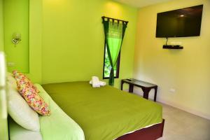 a green bedroom with a bed and a television at The House at Pranburi in Pran Buri