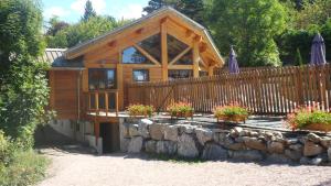 a wooden cabin with a fence and some flowers at Logis Hôtel Les Peupliers in Baratier