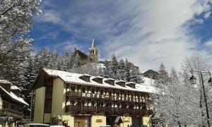 a building covered in snow with a church in the background at Hotel Castillan in La Grave