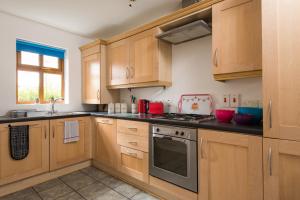 a kitchen with wooden cabinets and a stove top oven at Big Fish Homes - The Cloisters in Belfast