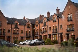 a row of brick buildings with cars parked in a parking lot at Big Fish Homes - The Cloisters in Belfast