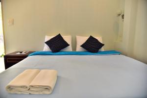 Un dormitorio con una cama blanca con toallas. en The House at Pranburi, en Pran Buri