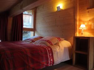 een slaapkamer met een bed in een blokhut bij La maison de Marie in Valmorel