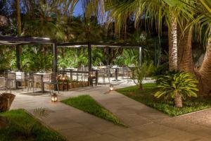 un patio con tavoli, sedie e palme di Hotel Barracuda a Marina di Campo