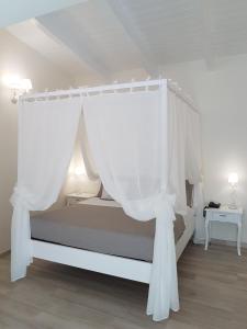 - une chambre avec un lit à baldaquin et des rideaux blancs dans l'établissement Finestre sul Borgo, à Cassano delle Murge