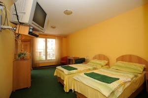 a hotel room with two beds and a flat screen tv at Hotel City in Pardubice