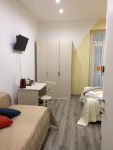 Cette chambre comprend deux lits, un bureau et une table. dans l'établissement La Perla Del Golfo, à La Spezia