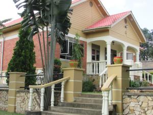 une maison avec un palmier en face dans l'établissement Namugongo Holiday Home, à Kasiyirize