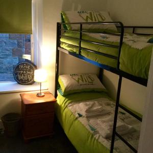 a room with two bunk beds and a table with a lamp at In House Garden Flat in Castle Douglas