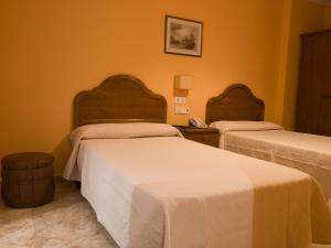 two beds in a room with orange walls at Hotel Marcial in Narón