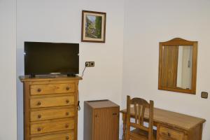 einen TV auf einer Kommode mit einem Holztisch in der Unterkunft Hotel Balcón de Cazorla in Cazorla