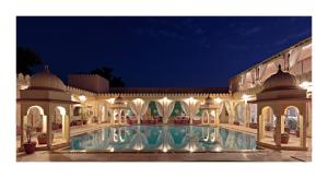 a large building with a swimming pool at night at Rohet Garh in Rohat