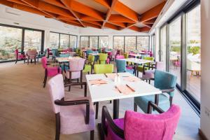 um restaurante com mesas, cadeiras e janelas em Hotel Borovnik em Tisno
