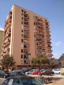 Un edificio alto con coches aparcados en un estacionamiento. en Perla 5, primera línea de playa y centrico, en Fuengirola